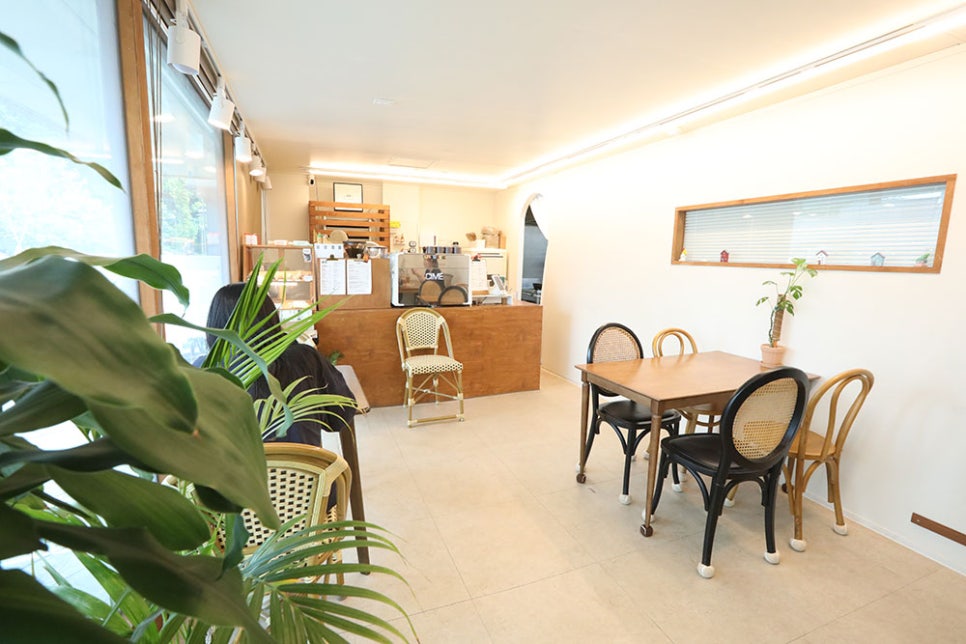 모던하고 세련된 내부 모습. 목제 테이블과 의자 그리고 우드톤 인테리어와 초록 초록한 식물 덕분에 자연친화적인 느낌과 따뜻하고 아늑한 분위기를 자아냅니다.